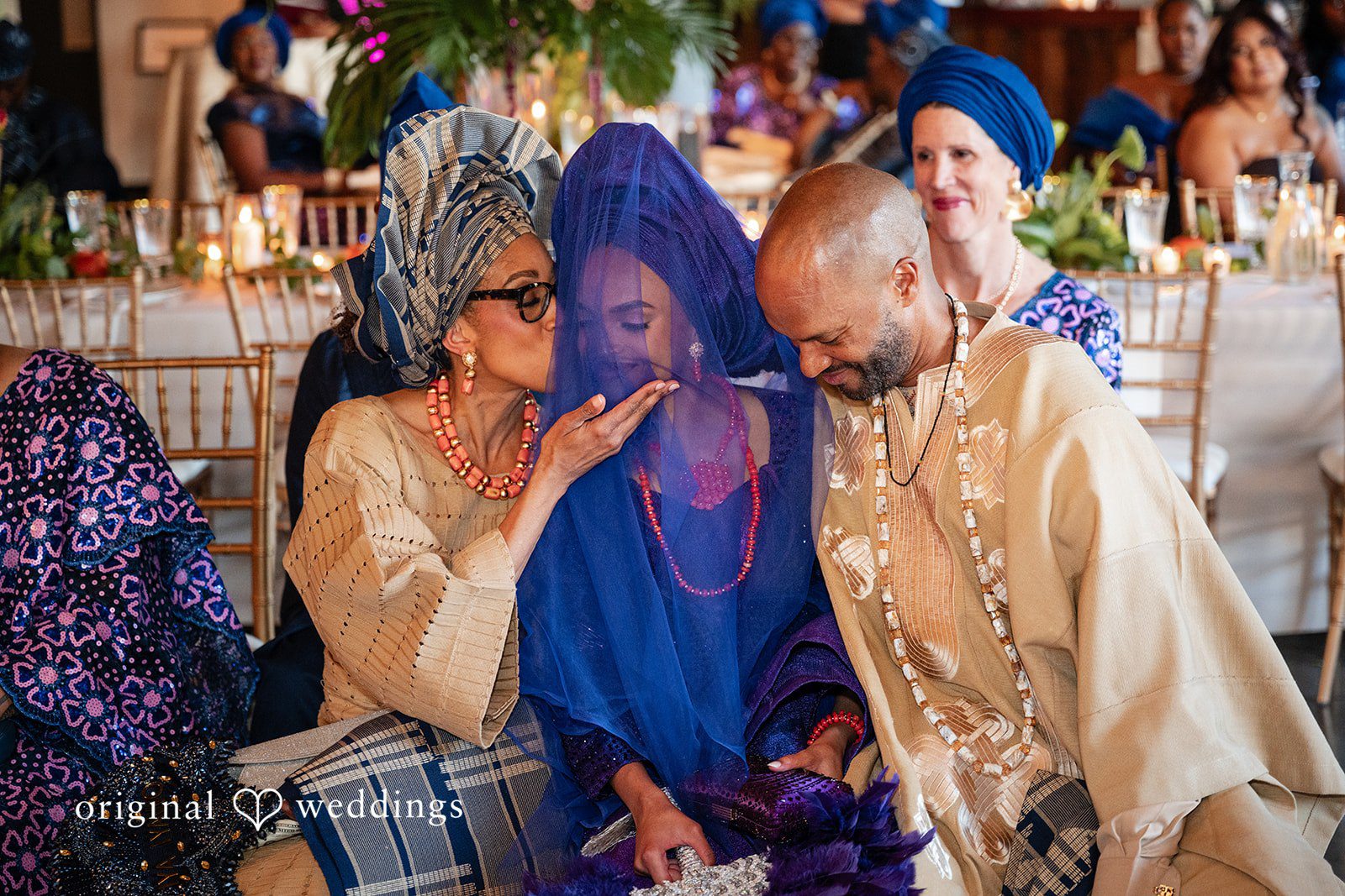 A man in a gold outfit interacting with a woman wearing a blue headwrap.