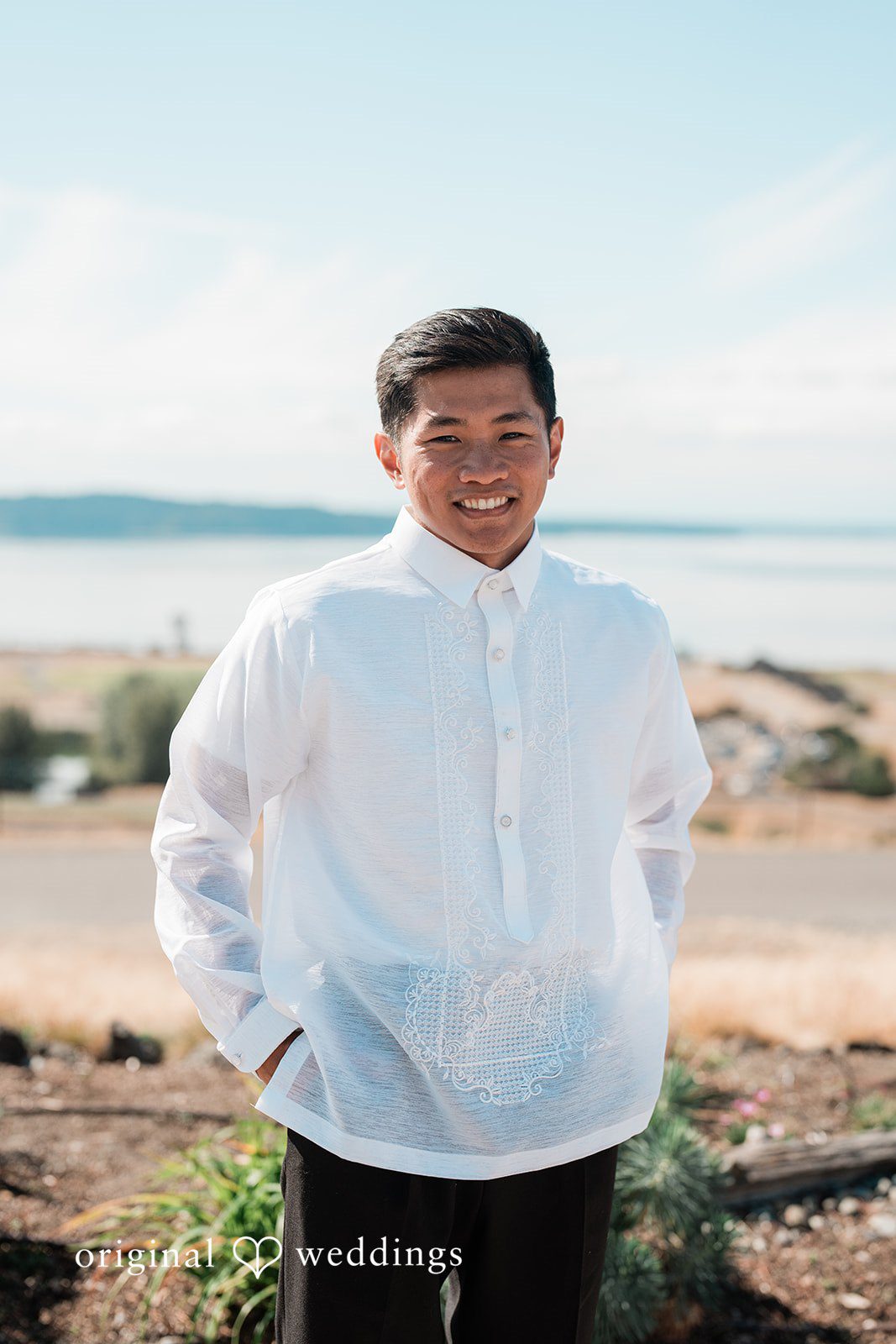 Katie + Gerald A portrait of a groom wearing a white barong tagalog shirt by the coast.