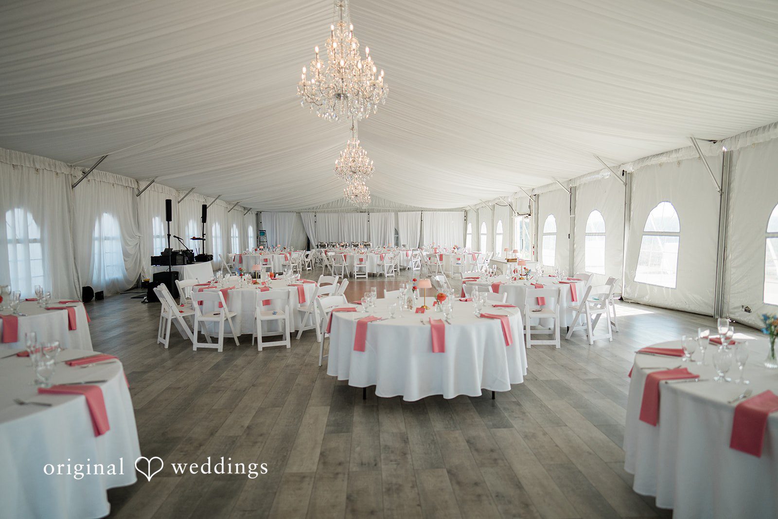 Katie + Gerald A large banquet hall arranged with round dining tables draped in white linens.