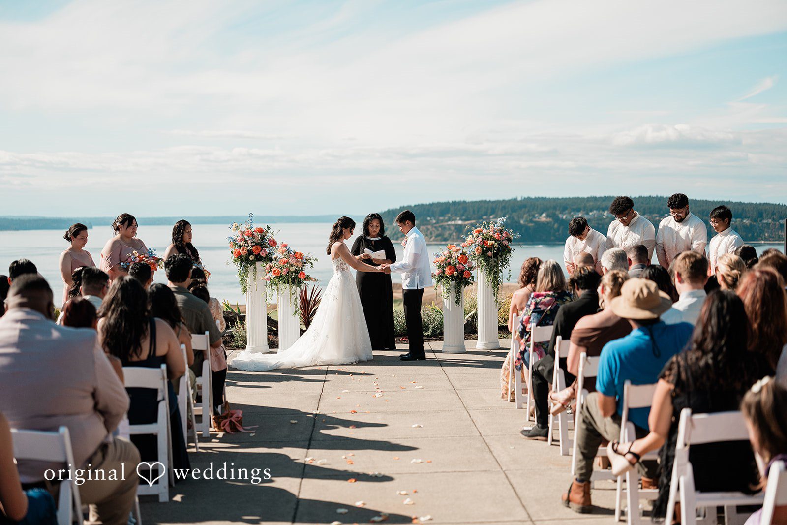 Katie + Gerald A wedding ceremony in progress with guests seated on both sides of the aisle.
