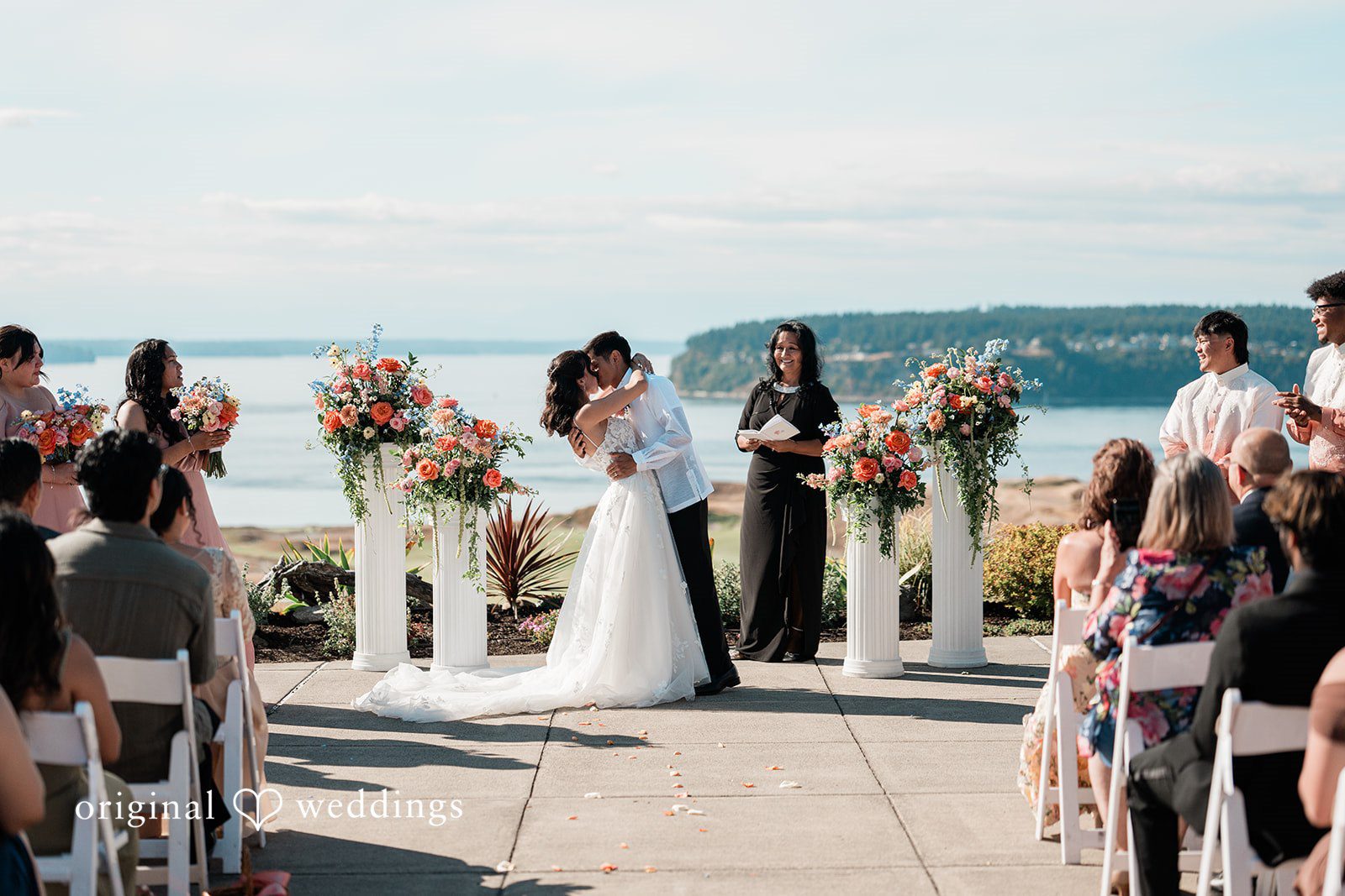 Katie + Gerald A wide shot of a wedding ceremony taking place on a coastal cliff.