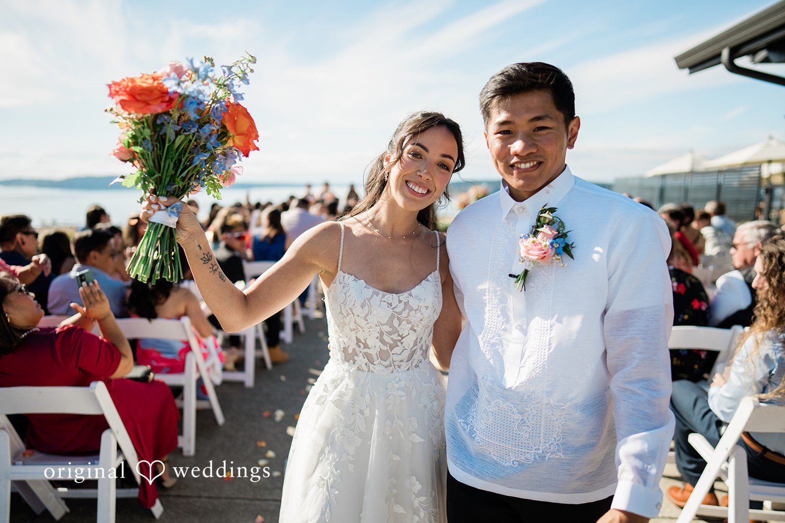 Katie + Gerald A bride and groom smiling together with vibrant flowers in the foreground.
