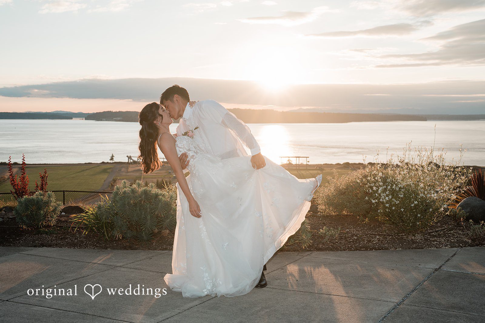 Katie + Gerald A groom holding his bride's hands as they share a moment by the waterfront.