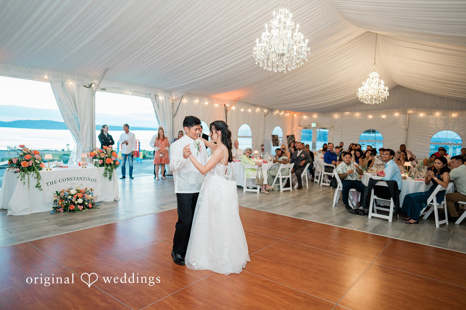 Katie + Gerald A bride and groom sharing a dance in the center of a crowded reception hall.