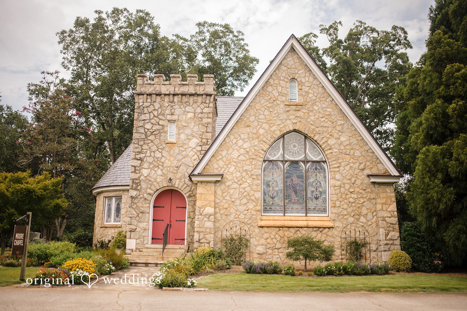 Julie + Joshua A small stone church building with a peaked roof surrounded by green trees.