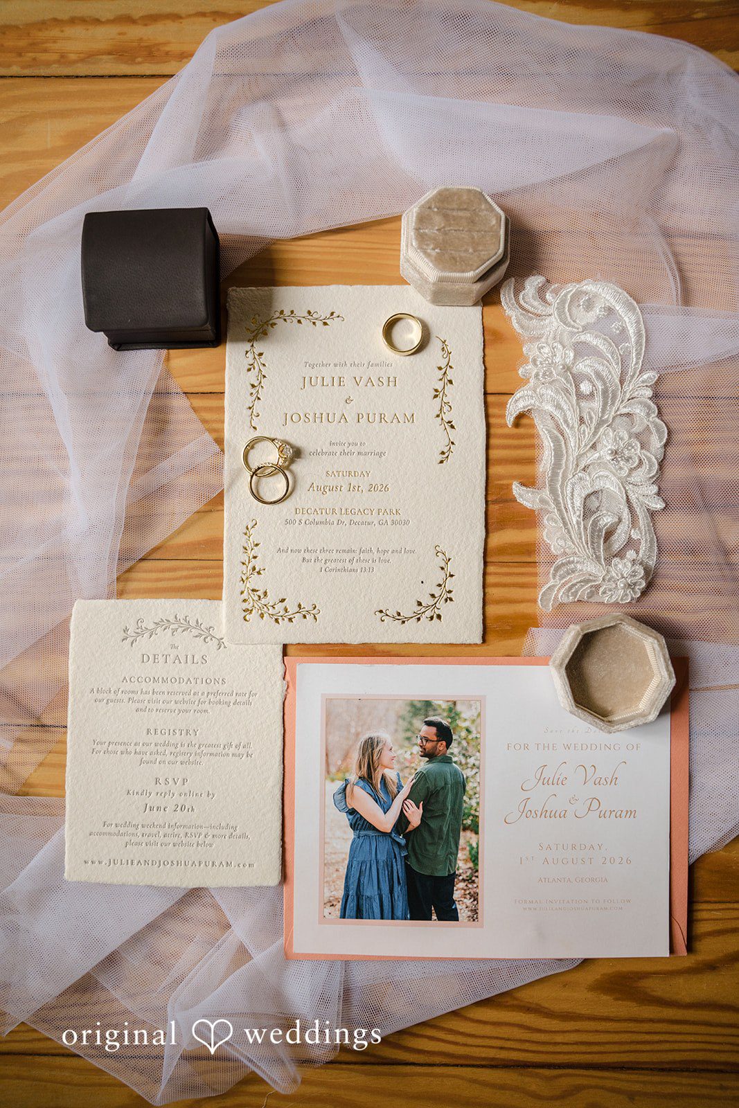 Julie + Joshua A collection of elegant wedding stationery items, rings, and invitations laid out on a fabric surface.