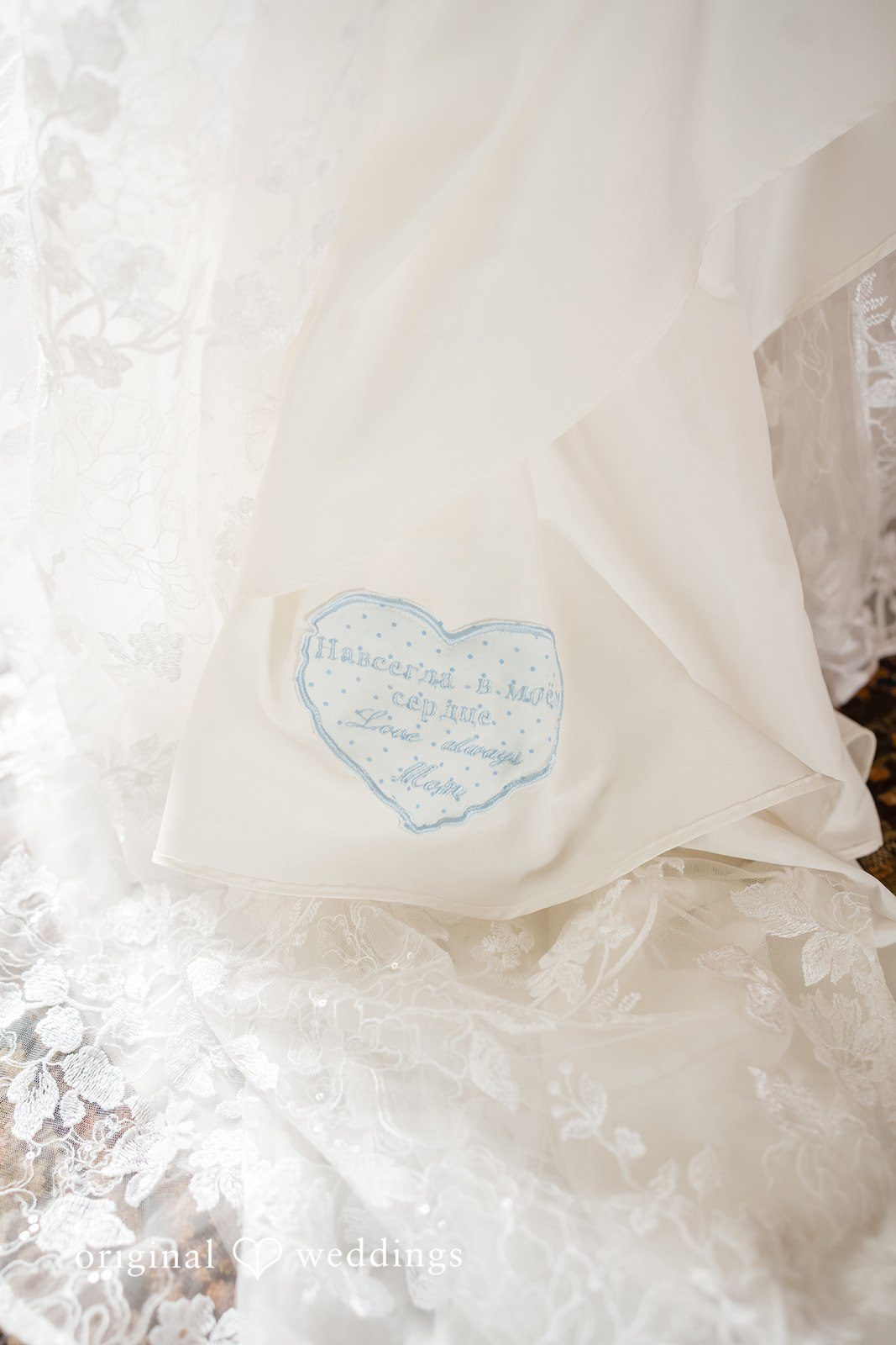 Julie + Joshua A close-up of the delicate lace fabric details on a white wedding dress.