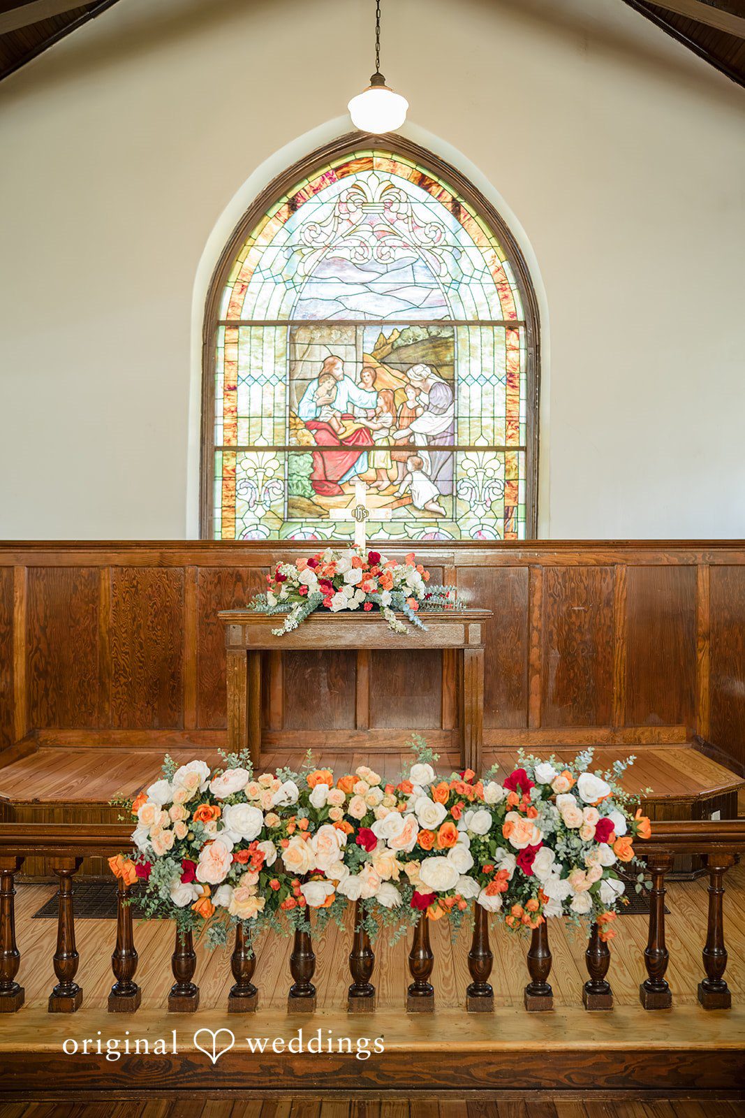 Julie + Joshua A church altar area decorated with low rows of white and pink flowers.