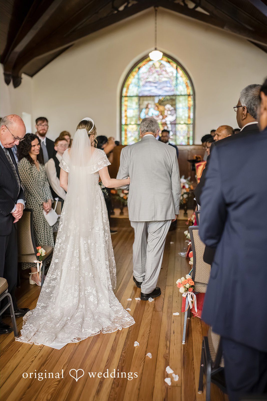 Julie + Joshua A bride walking down the church aisle toward the altar as guests look on.