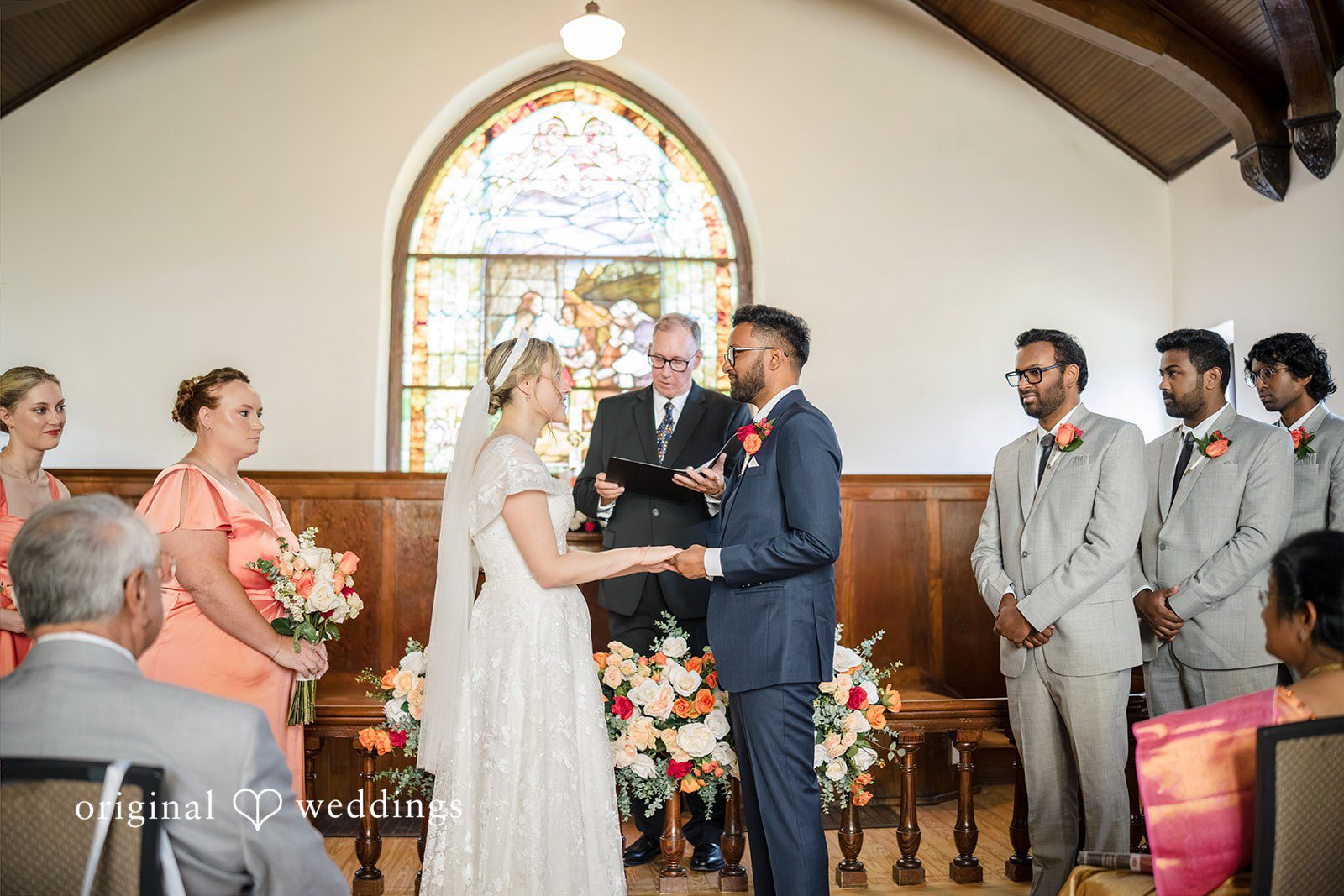Julie + Joshua A wedding ceremony taking place at the altar with the bridal party standing alongside.