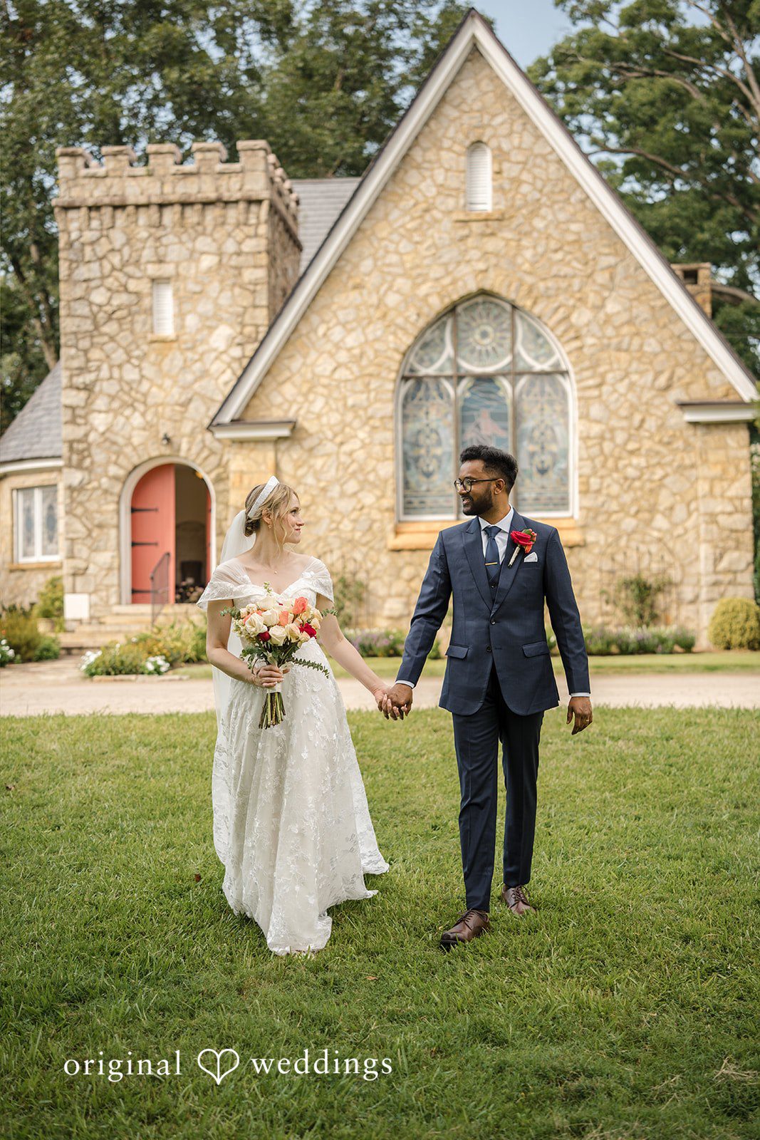 Julie + Joshua A bride and groom walking hand-in-hand toward a stone church building.
