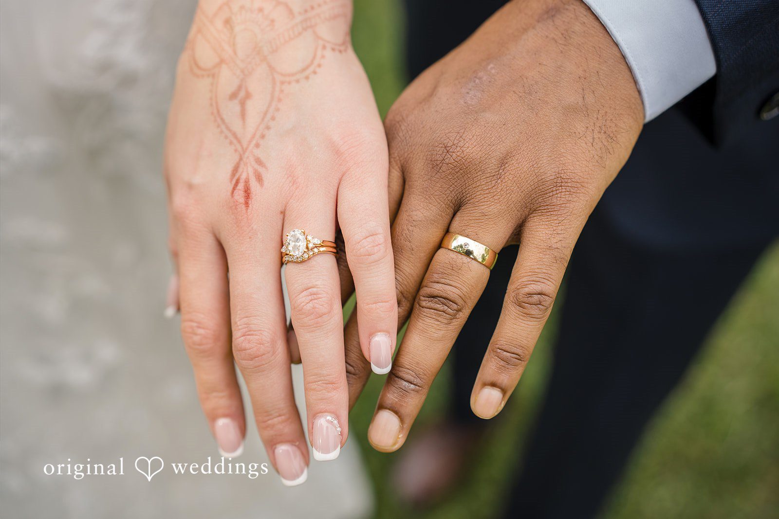 Julie + Joshua A close-up of a bride and groom holding hands to show off their wedding rings.