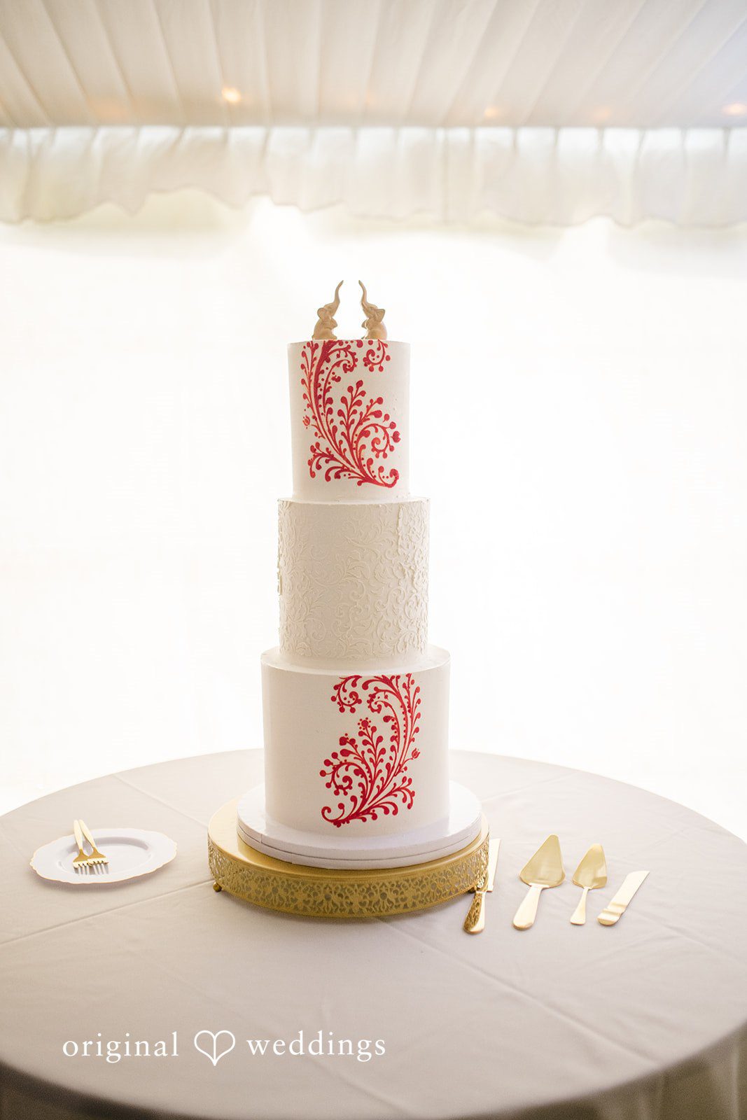 Julie + Joshua A three-tiered white wedding cake decorated with pink flowers on a round stand.