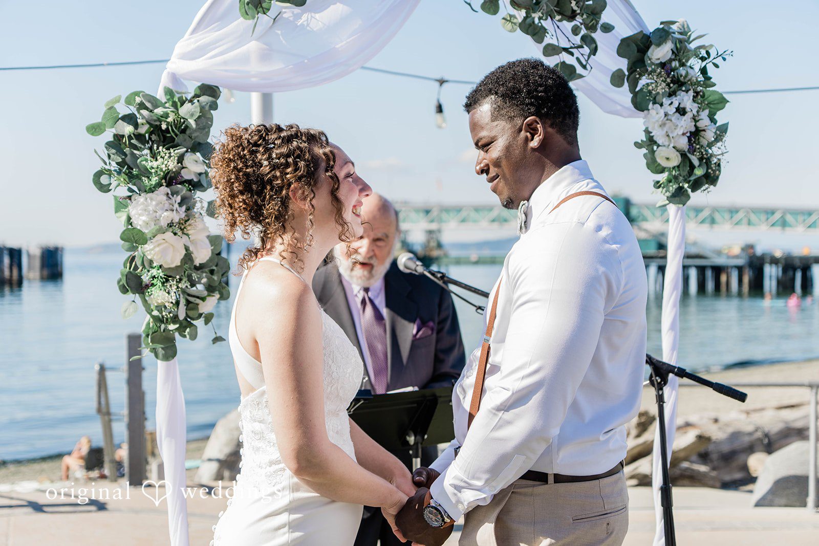 Naomi + Darrell Bride and groom standing together looking at each other by the water.