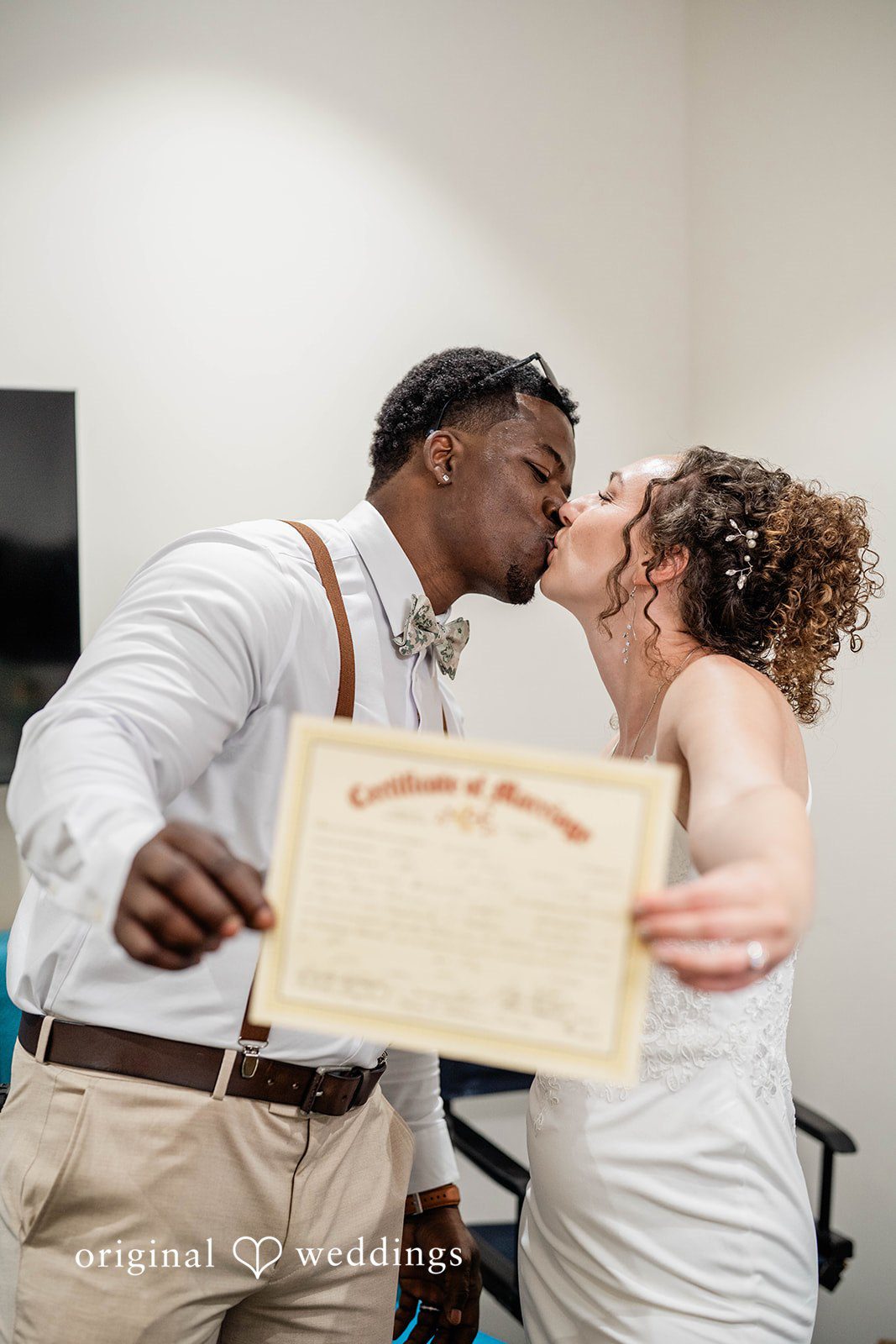 Naomi + Darrell Newlyweds kissing while holding up their signed marriage certificate.