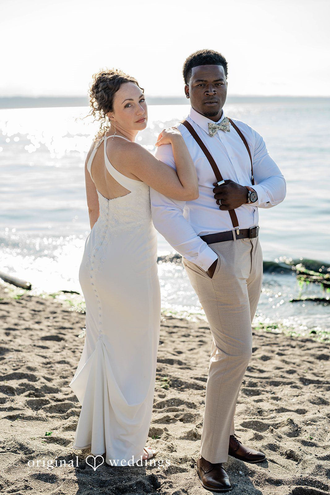 Naomi + Darrell Bride and groom standing together on a sandy beach.
