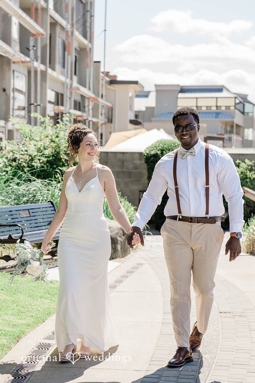 Naomi + Darrell Newlyweds walking hand-in-hand along a wooden pier.