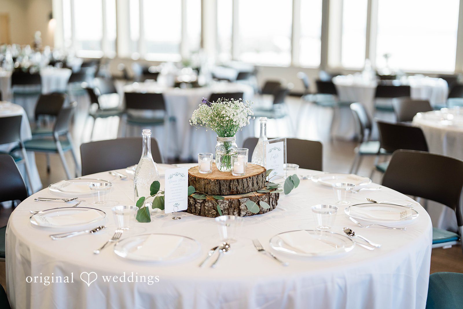 Naomi + Darrell Reception table decorated with white linens and a rustic wooden centerpiece.