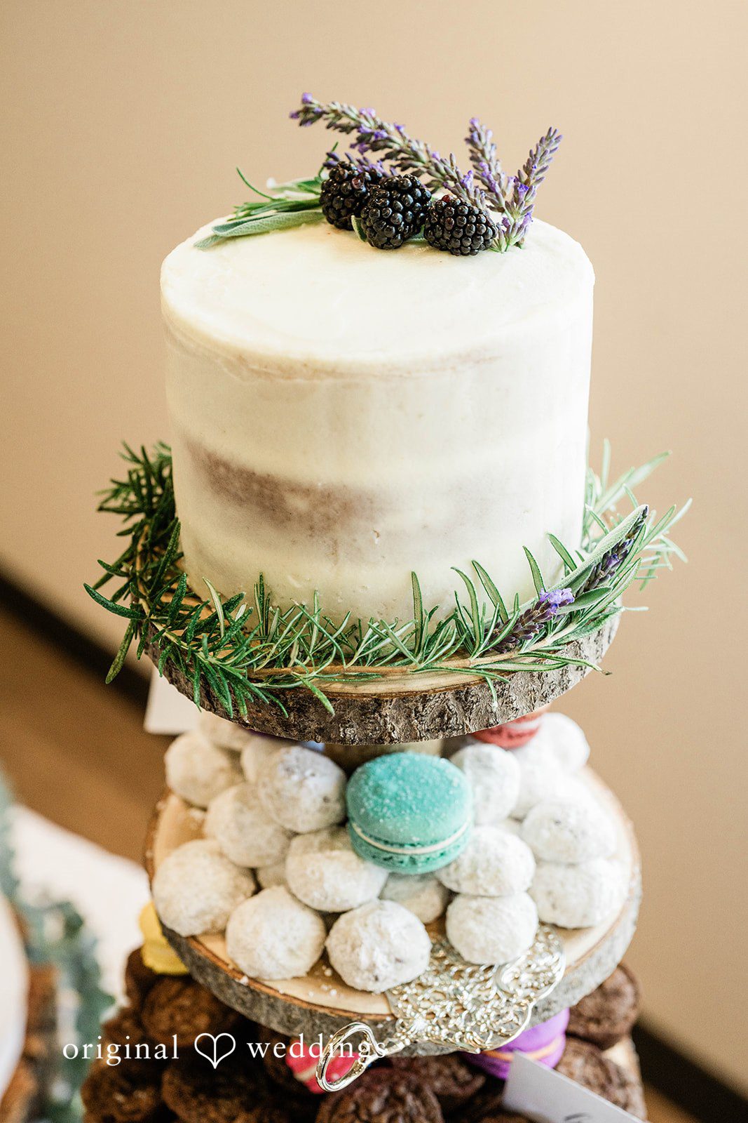 Naomi + Darrell Multi-tiered white wedding cake decorated with fresh green foliage.