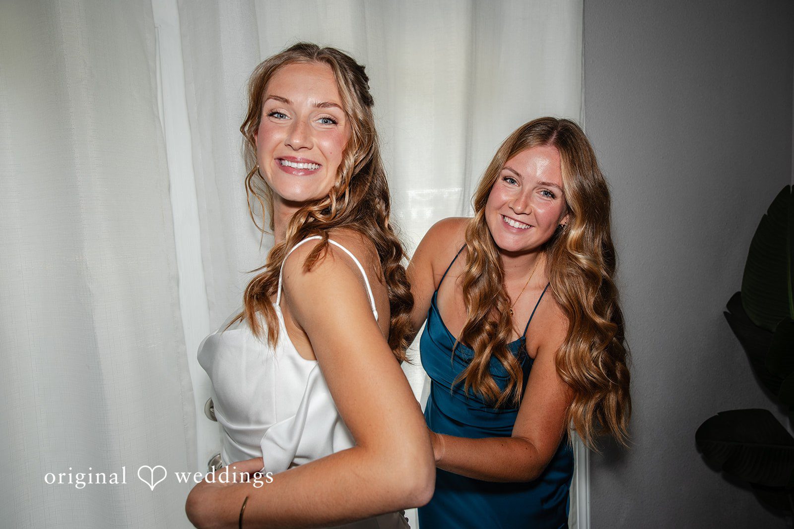 Alissa + Duncan A bride and a bridesmaid smiling and posing together before the wedding.