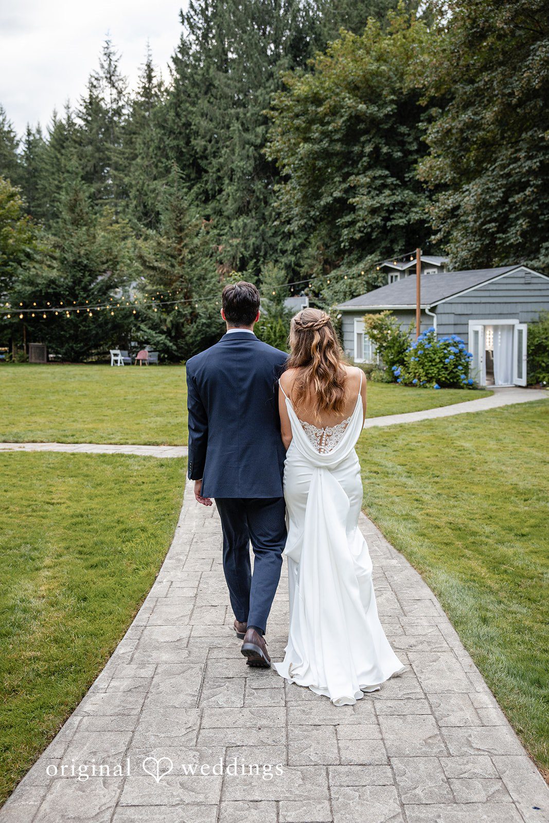 Alissa + Duncan A bride and groom walking away down a stone path toward a building.