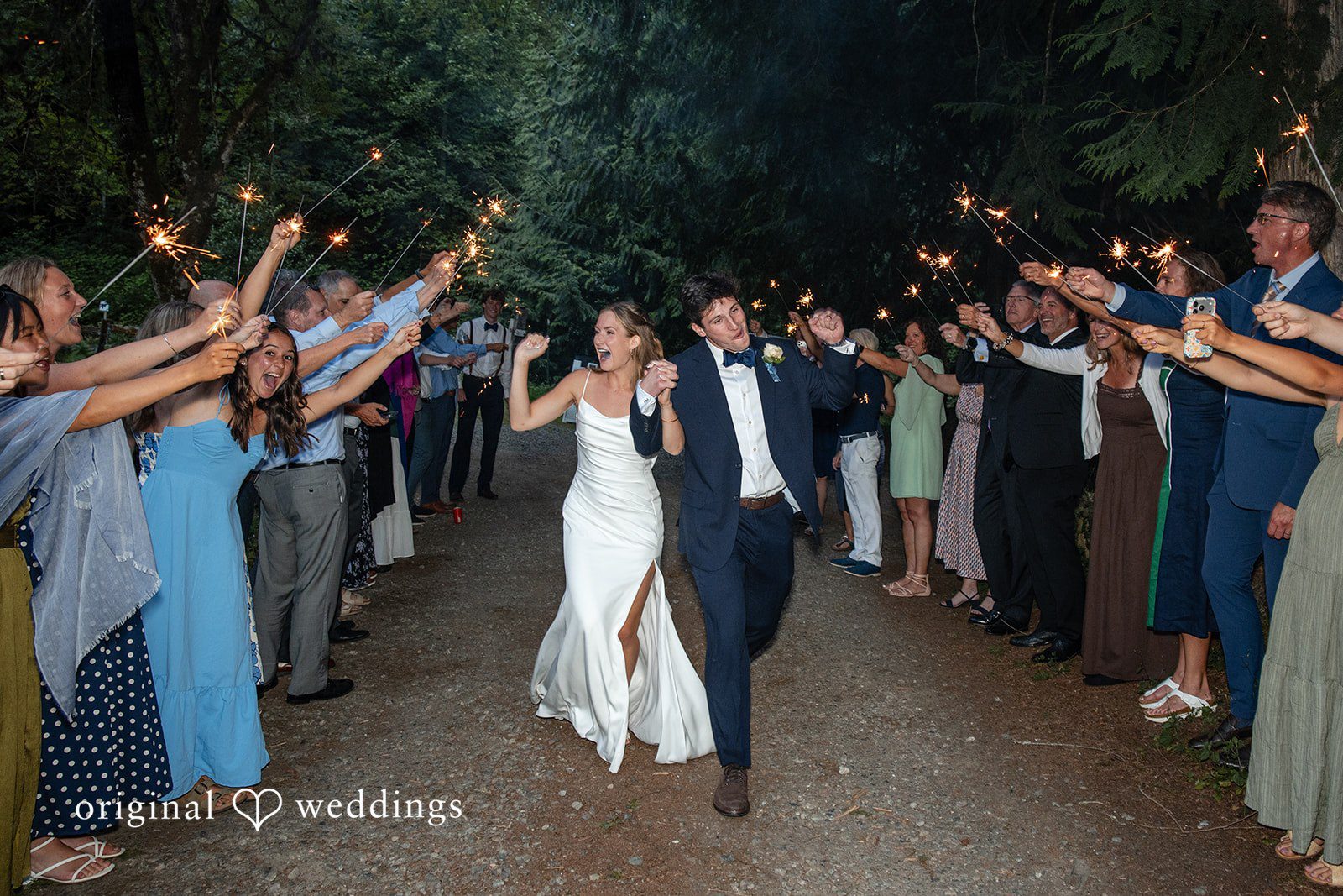 Alissa + Duncan A newly married duo walking through a sparkler exit as guests cheer them on.