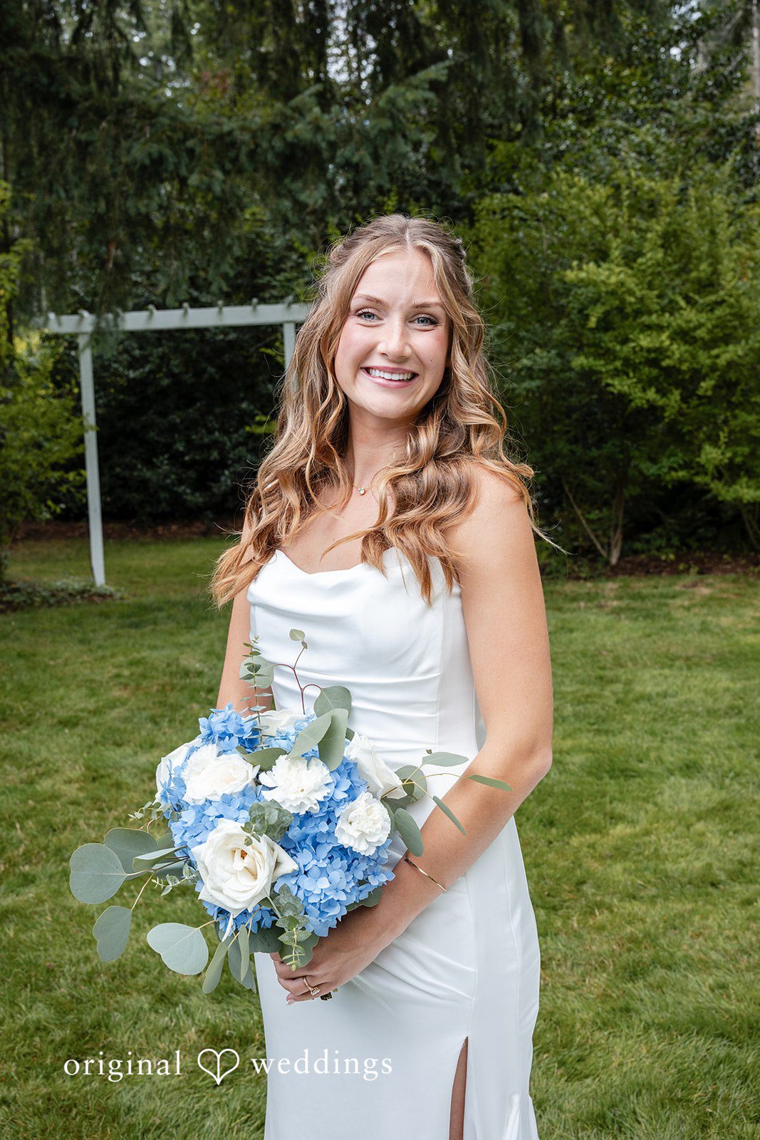 Alissa + Duncan A smiling bride holding her bouquet while standing in front of a green backdrop