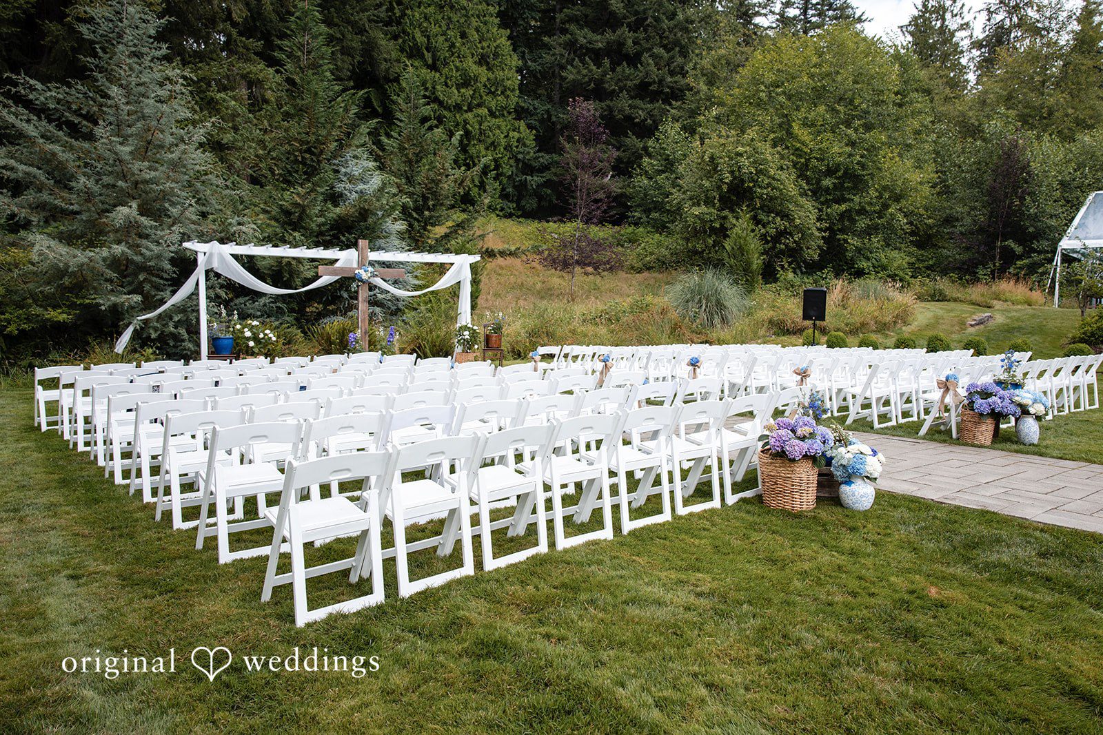 Alissa + Duncan A wedding ceremony setup with rows of white chairs facing a fabric-draped altar.