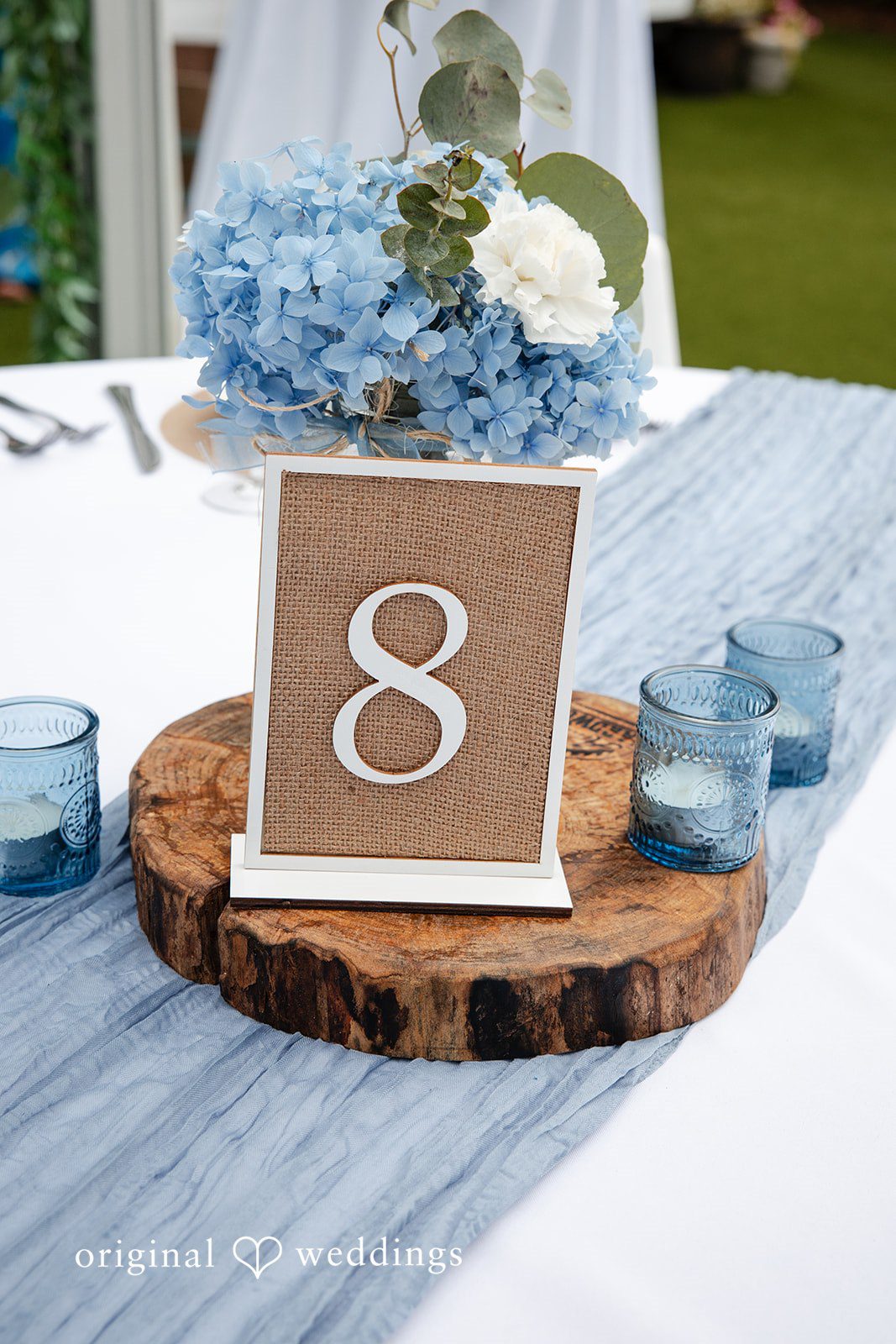 Alissa + Duncan A rustic wooden table number card displaying the number eight on a slice of wood log.