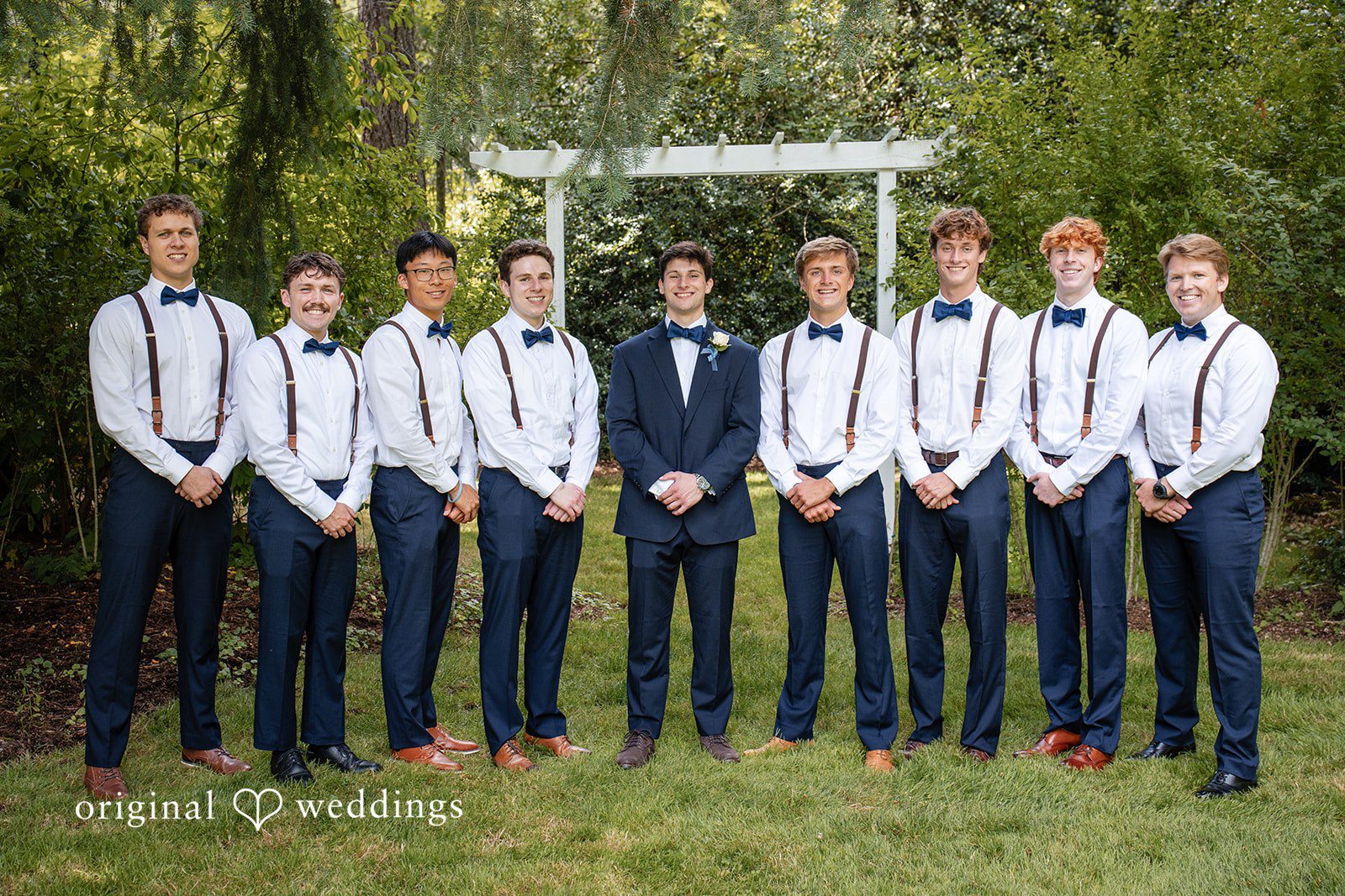 Alissa + Duncan A groom posing with his groomsmen wearing matching blue trousers, white shirts, and suspenders.