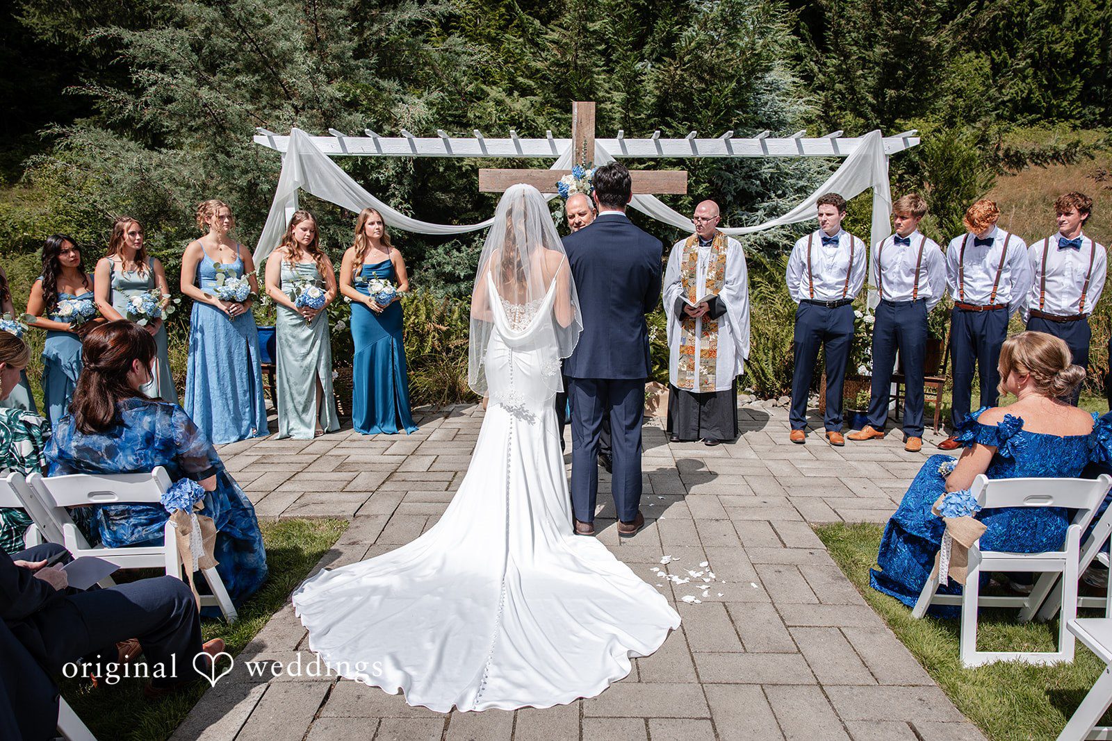 Alissa + Duncan A wide view of a wedding ceremony with the bride and groom standing at a white arch.