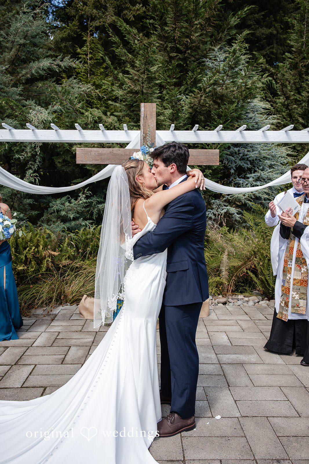 Alissa + Duncan A bride and groom sharing a hug in front of a white wooden structure.