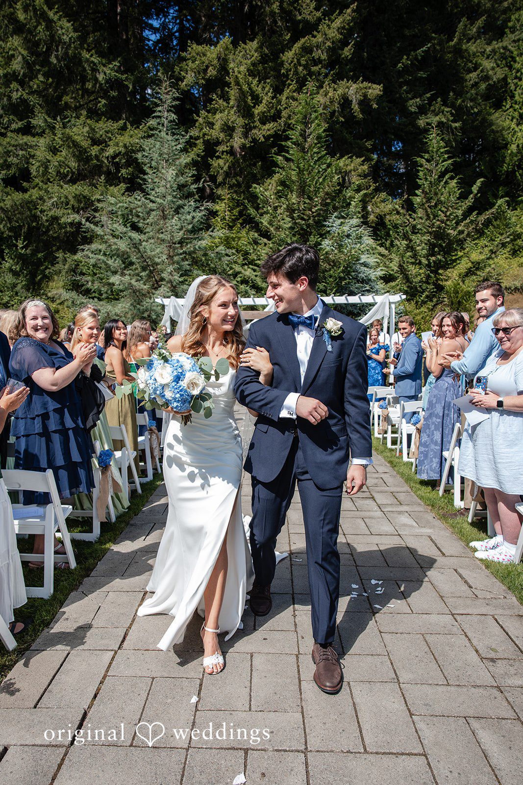Alissa + Duncan A bride and groom walking hand-in-hand down a paved path after getting married.