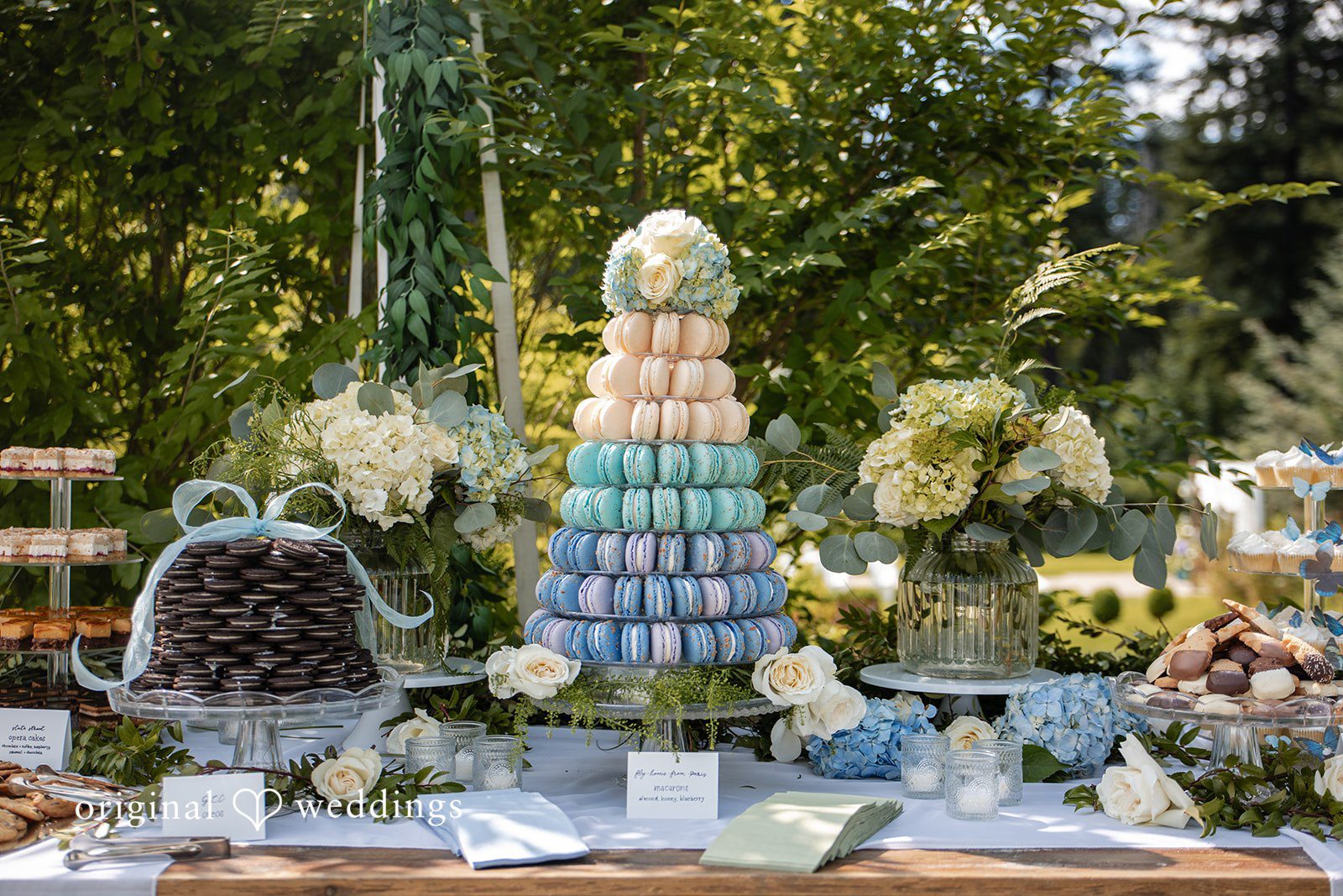 Alissa + Duncan A dessert tower surrounded by decorative wedding treats and floral arrangements.