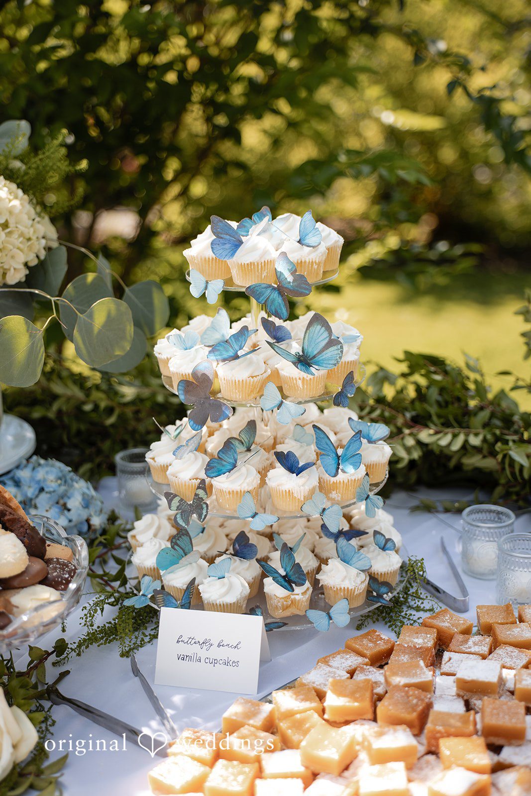 Alissa + Duncan A dessert table display filled with cupcakes and assorted sweet treats at a reception.