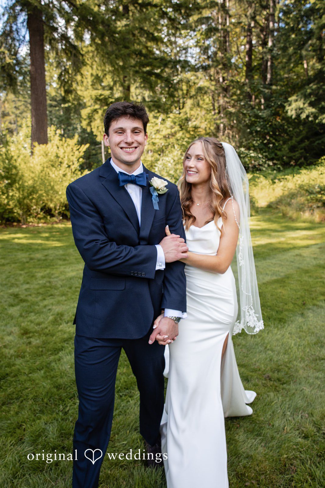 Alissa + Duncan A bride and groom standing side-by-side against a backdrop of green foliage.