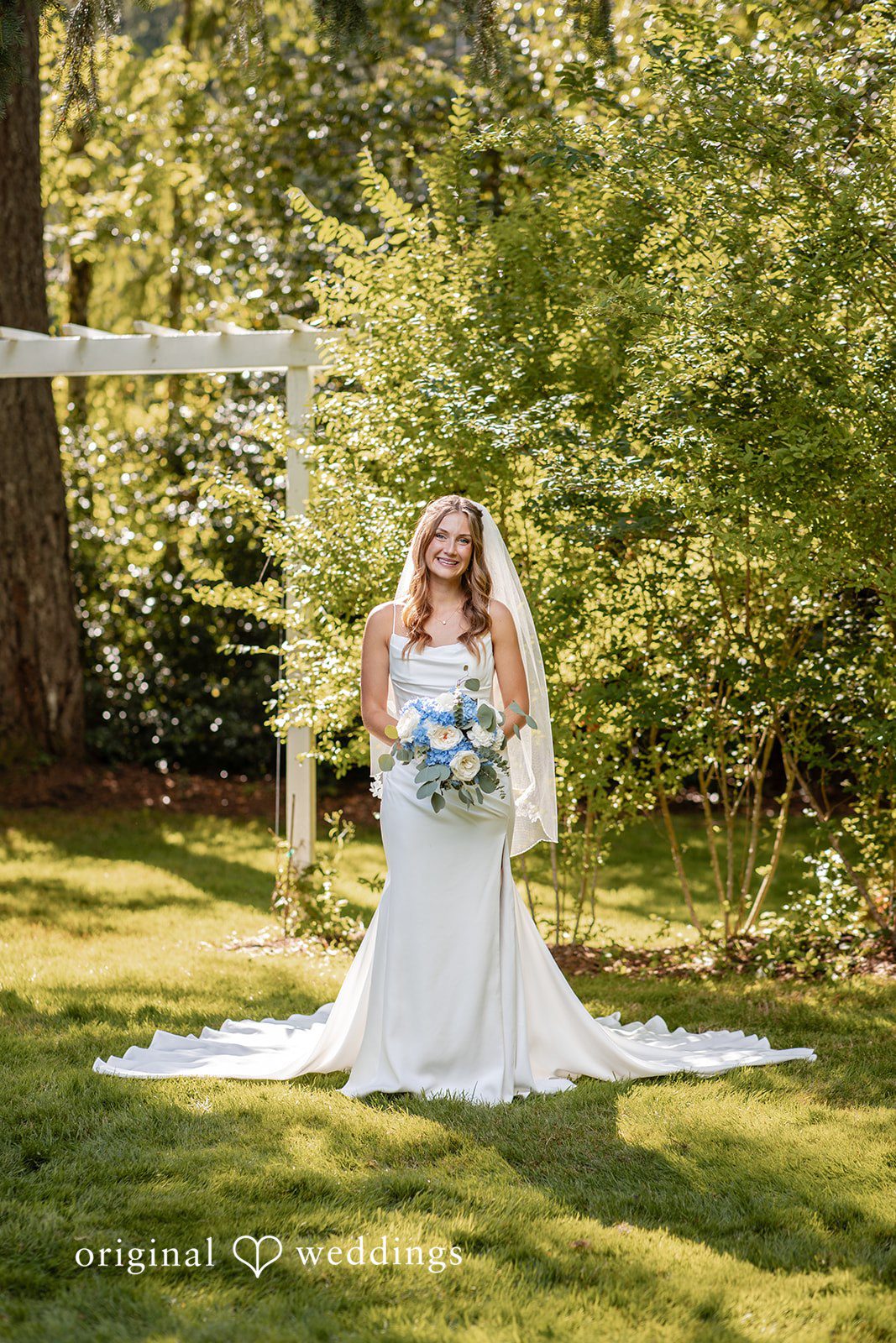 Alissa + Duncan A bride standing on a grassy path holding her bridal bouquet.