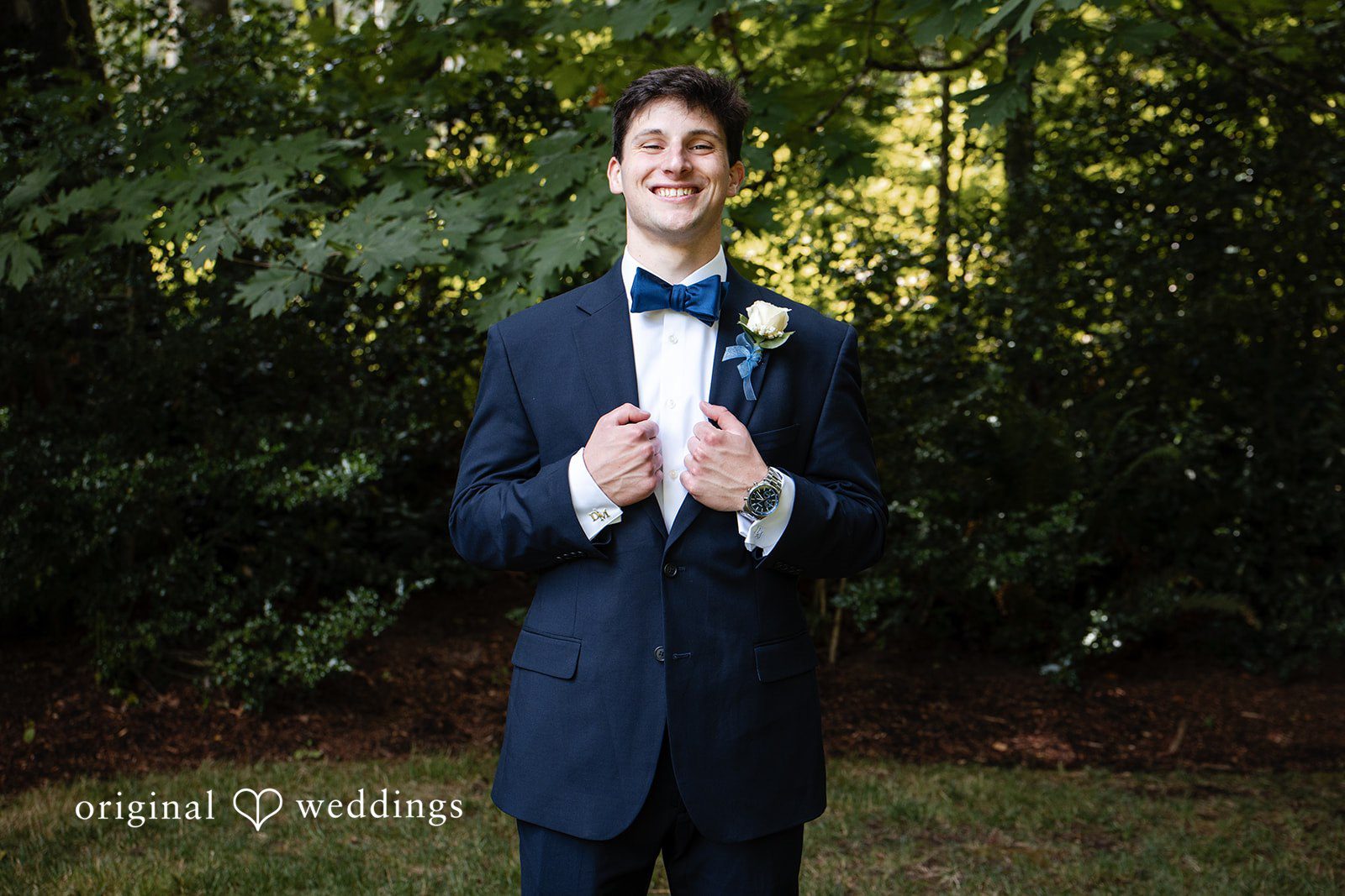 Alissa + Duncan A groom in a dark suit and bow tie posing against a natural background.