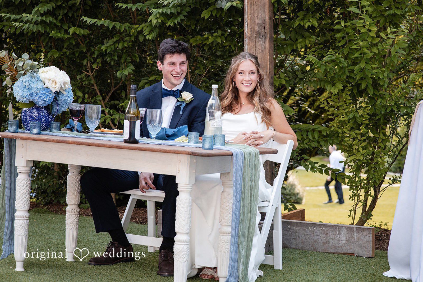 Alissa + Duncan A bride and groom sitting together at a decorated head table.