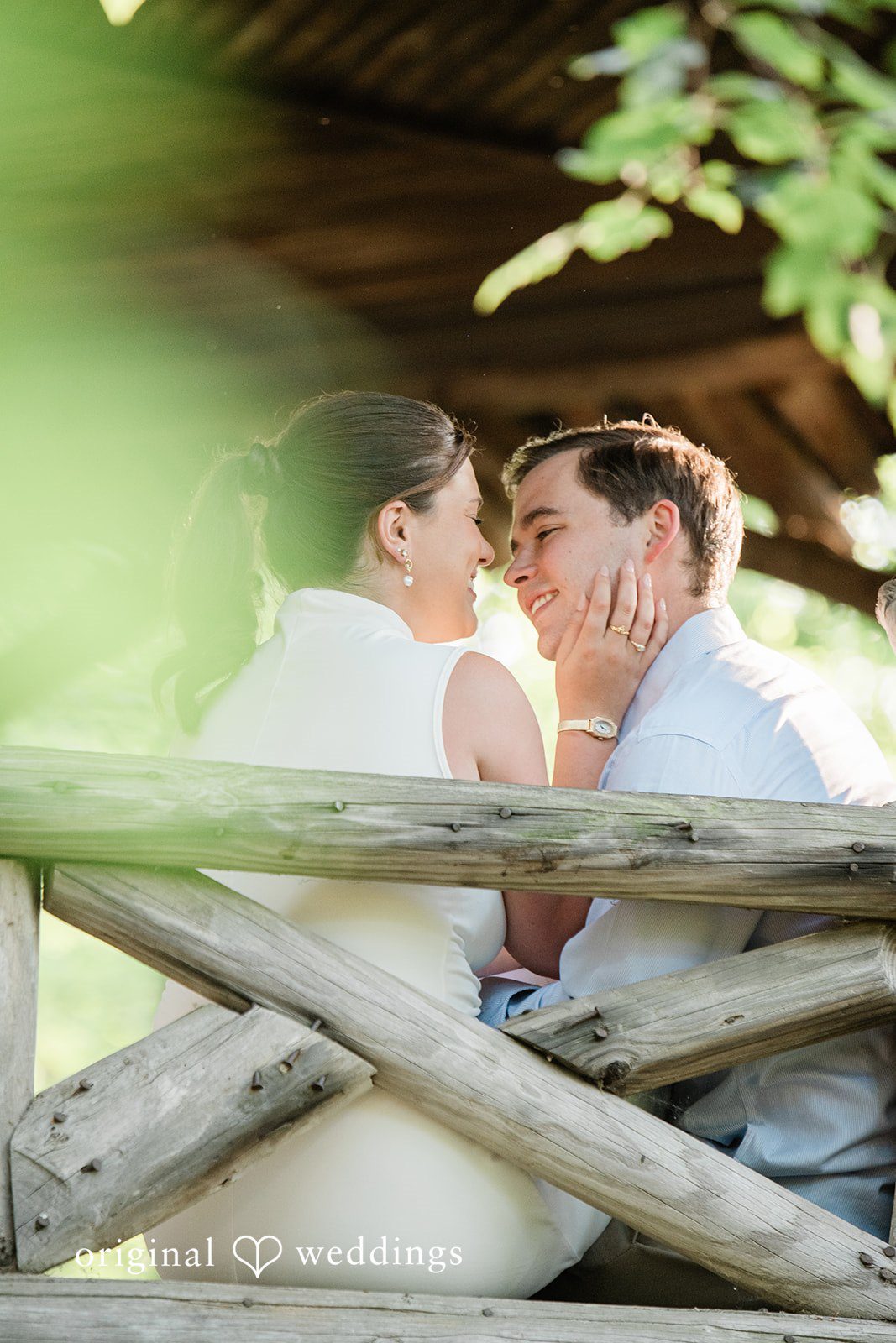 A couple sitting side-by-side on a rustic wooden log bench.