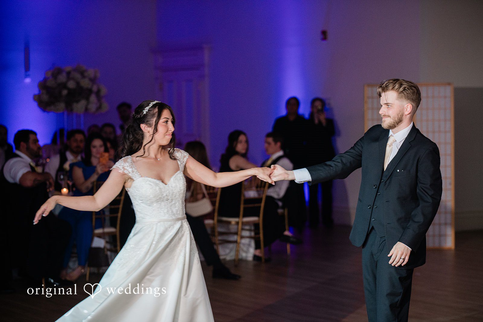 Julia + Camden A bride and groom hold hands while dancing at an evening reception.