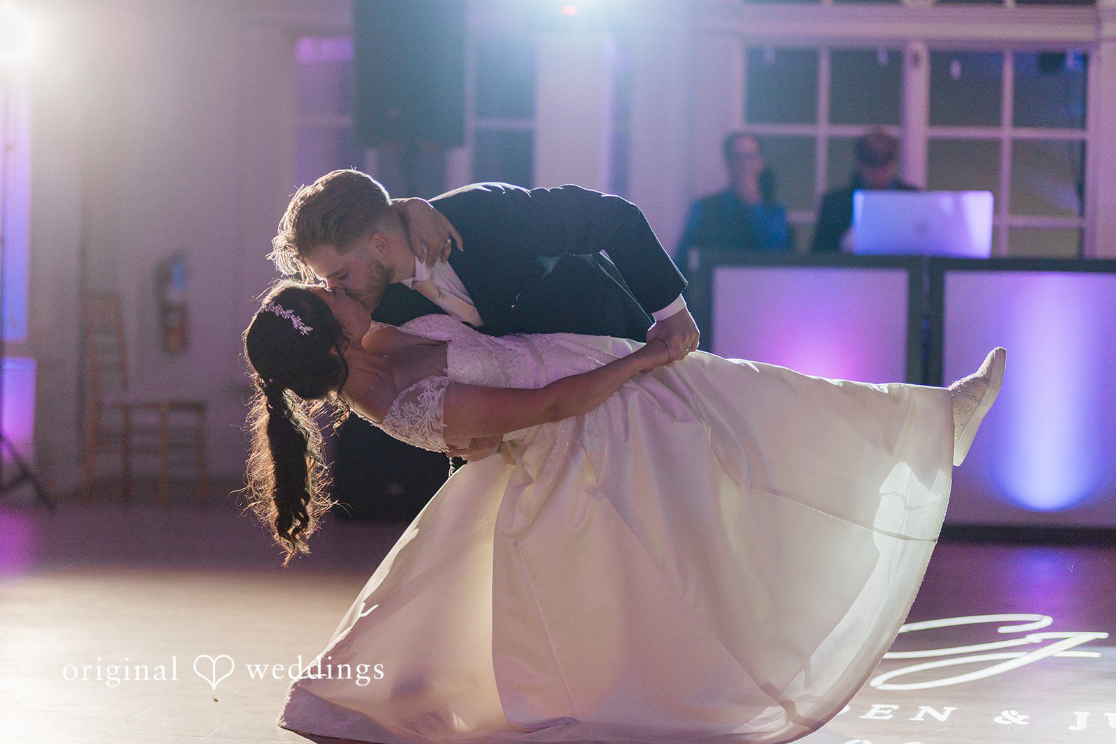 Julia + Camden A bride and groom share a close dance under soft blue reception lighting.