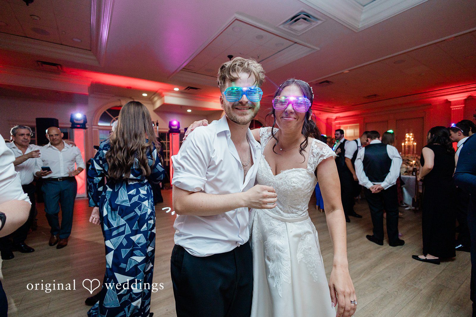 Julia + Camden A bride and groom wearing party glasses dance with their guests.