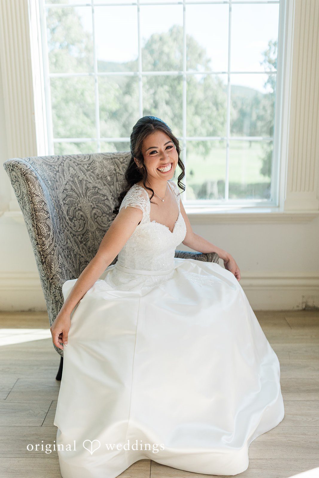Julia + Camden A bride seated in an armchair while wearing a white wedding gown.