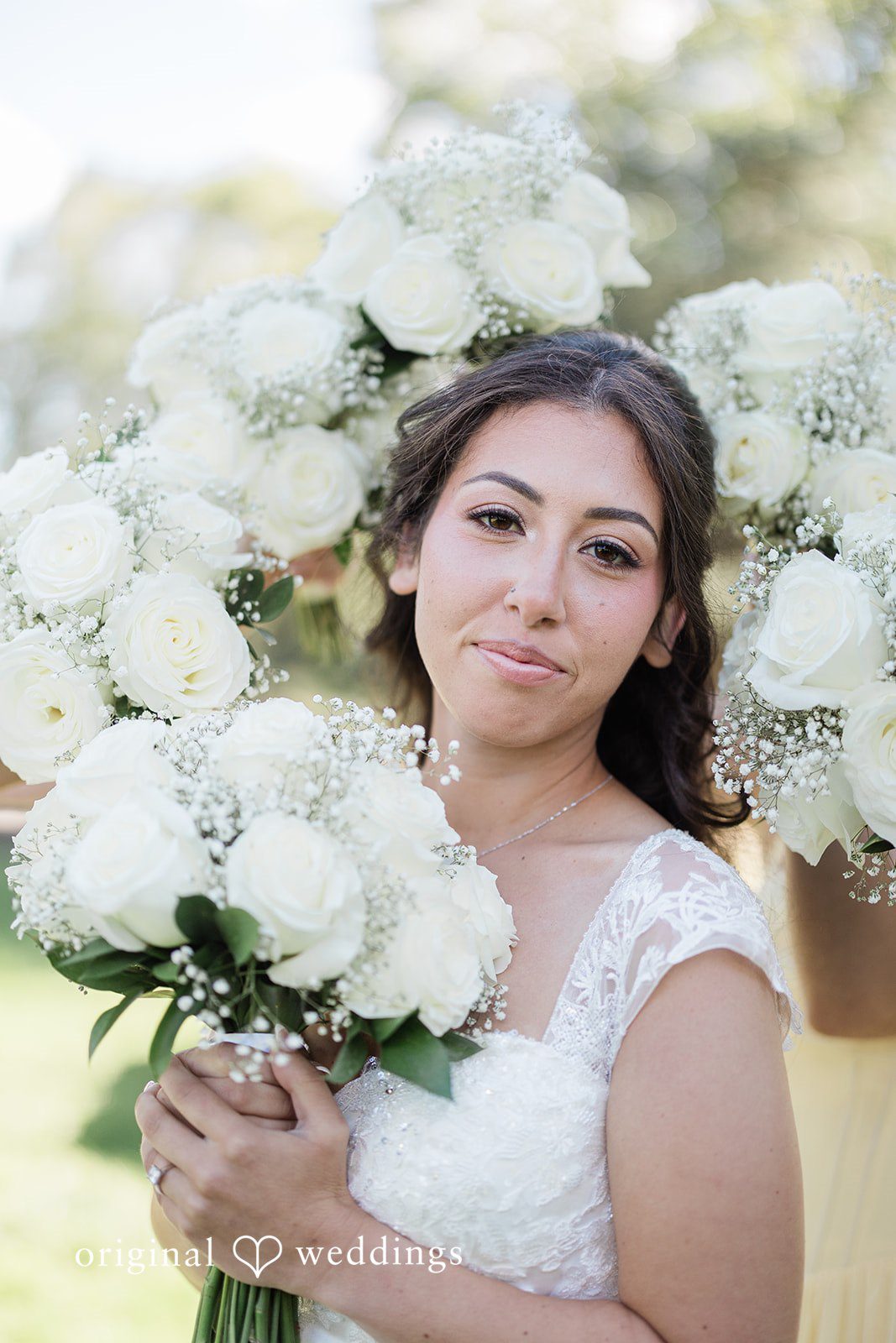 Julia + Camden A bride holding a large bouquet of white flowers while looking at the camera.