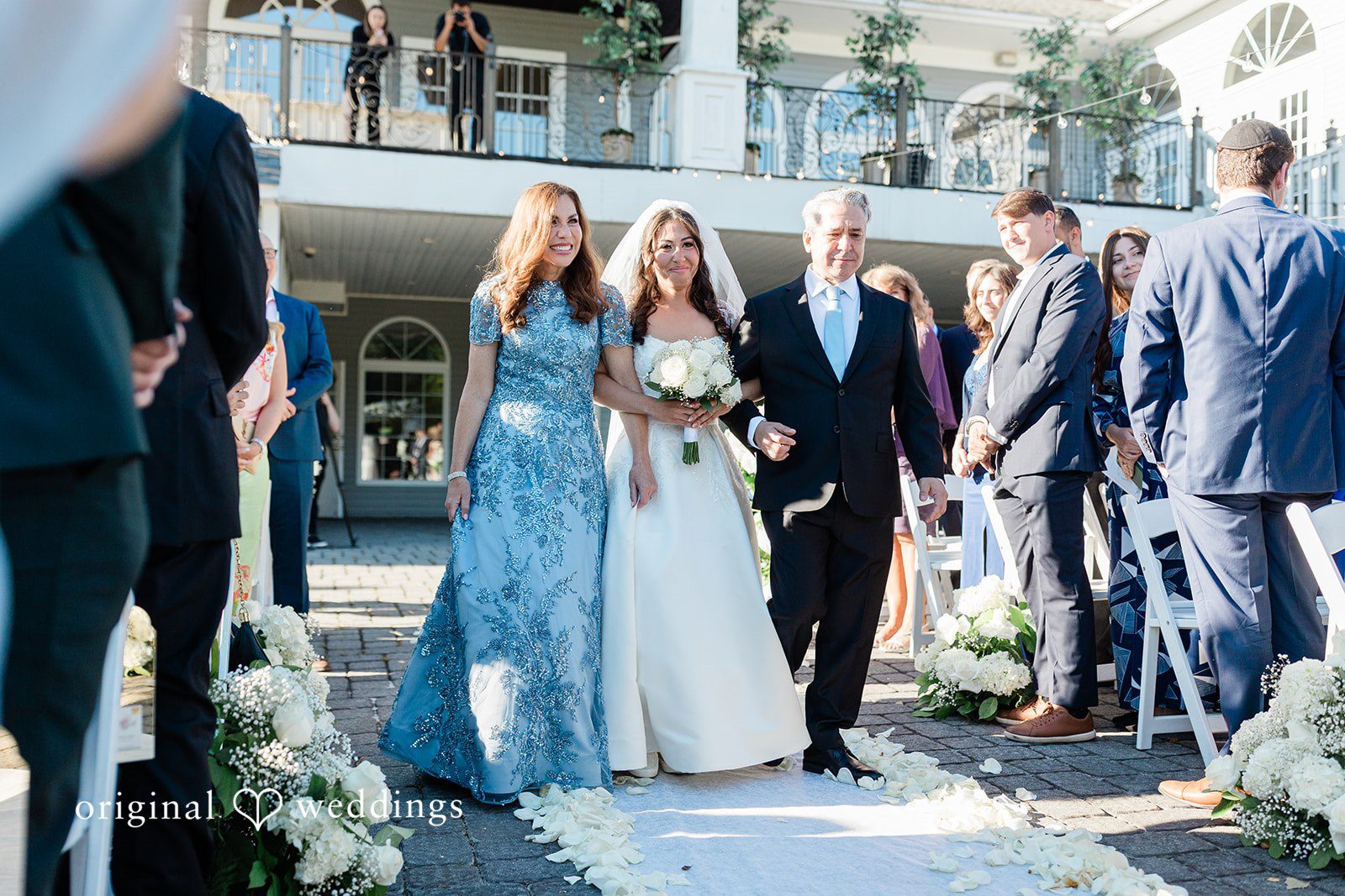 Julia + Camden A wedding party standing together on a path lined with trees.