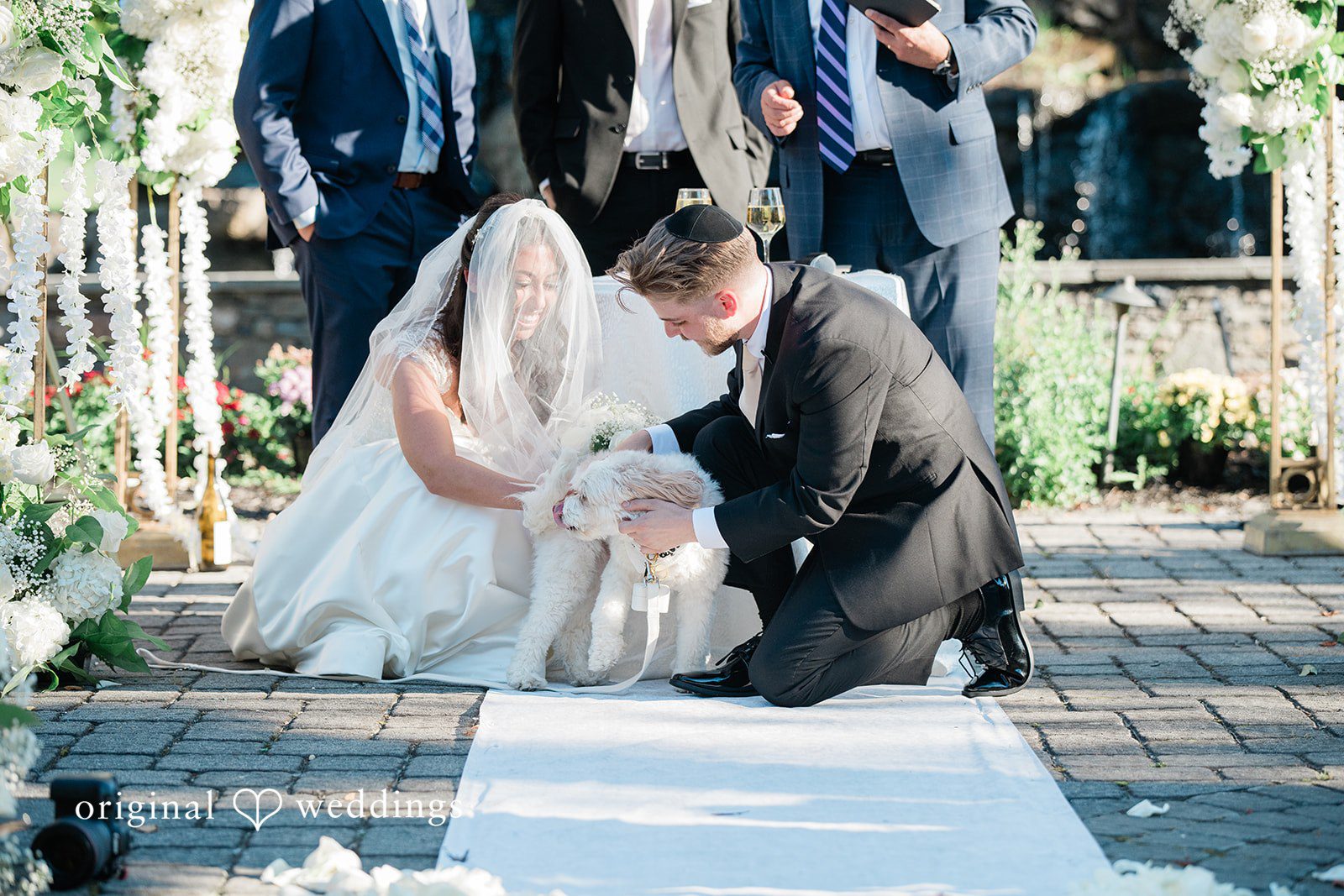 Julia + Camden A bride and groom walking down a white aisle runner after their ceremony.