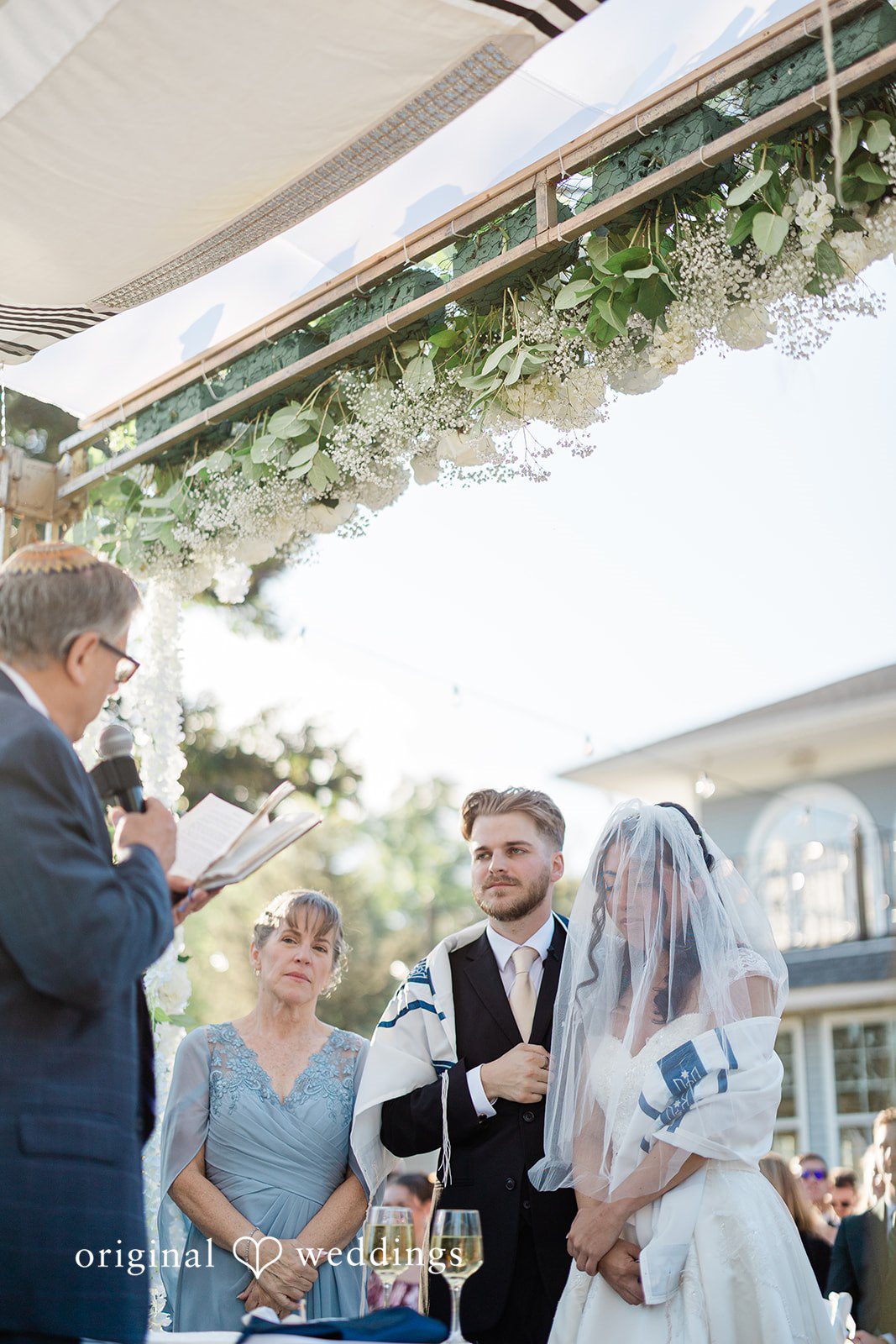 Julia + Camden A wedding party stands gathered together at the altar under an open structure.