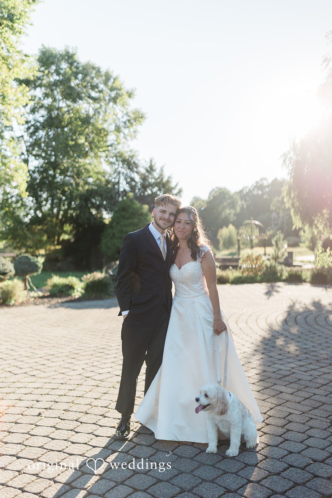 Julia + Camden A bride and groom walk together across a sunny, open lawn.