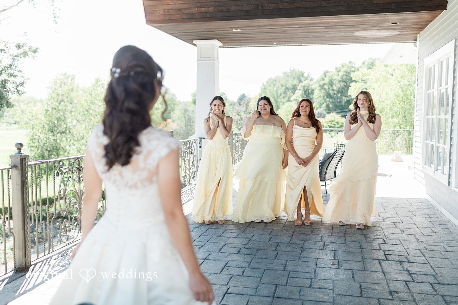 Julia + Camden A bride standing in profile under an open porch while bridesmaids walk behind her.